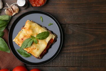 Delicious cooked lasagna and ingredients on wooden table, flat lay. Space for text