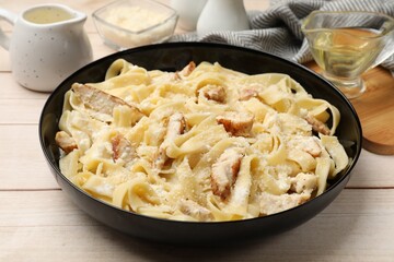 Tasty Alfredo pasta with chicken on light wooden table