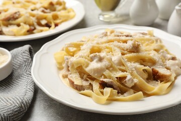 Tasty Alfredo pasta with chicken on gray textured table, closeup