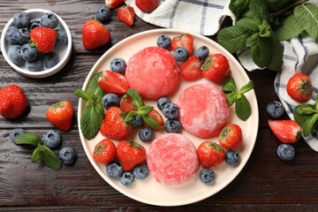 Delicious mochi, strawberries, blueberries and mint on wooden table, flat lay