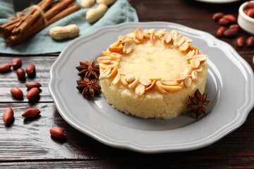 Delicious semolina halva with almond flakes and spices on wooden table, closeup