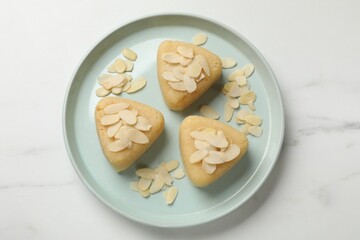 Pieces of delicious semolina halva with almond flakes on white marble table, top view