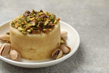 Delicious sweet semolina halva with pistachios on light grey table, closeup