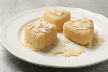 Pieces of delicious sweet semolina halva with almond flakes on light grey table, closeup