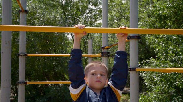 A boy is seen pulling himself up on a horizontal bar on a sunny day. Physical exercise at a young age can have many benefits for growing bodies. 