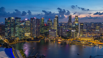 Fototapeta premium Aerial view of Singapore business district skyscrapers at evening with water reflections day to night timelapse
