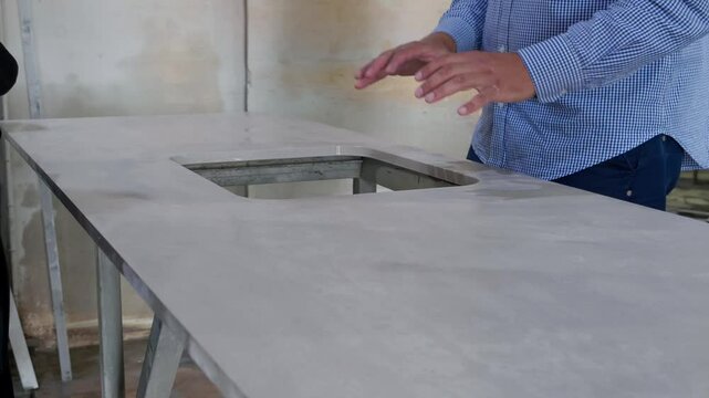 Experienced male quality control inspector examining and touching glossy surface of polished marble slab at quartz stone factory. Manufacturing kitchen countertop quartz