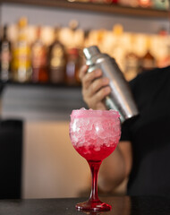 Bartender serving tequila sunrise alcoholic cocktail in glass on bar