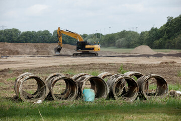 Construction site with excavator, drainage pipes, and earthmoving.  Land development in progress.