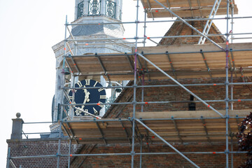 Scaffolding surrounds a historic building's tower with a clock.  Restoration or maintenance work is underway.