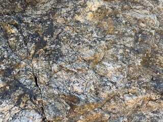 Mountain rock texture close-up background. Gray, black dark brown stone rock granite basalt texture background. Mountains surface. Close-up. Cracked broken crumbled. Rock texture wall.

