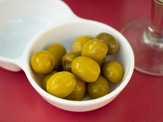 Large green olives with pits served to table in bowl