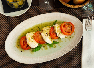 Delicious fresh caprese salad with mozzarella served with arugula on plate