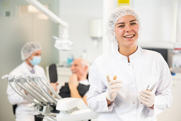 Young woman nurse posing while examining patient in dental clinic