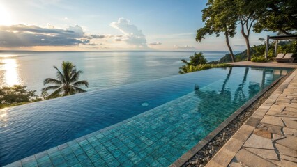 Tranquil blue infinity pool merging with the vast ocean at sunset, surrounded by lush tropical vegetation and palm trees, creating a luxurious and serene vacation getaway
