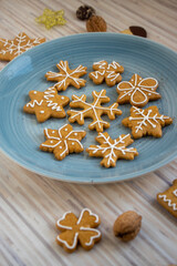 Painted traditional Christmas gingerbreads arranged on blue plate on white wooden table, various xmas shapes