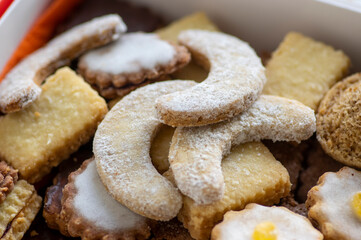 Various traditional Christmas sandbakelse, gingerbread and vanillekipferl arranged in white and red box on stars tablecloth