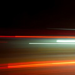 Abstract Motion Blur of Red and White Light Streaks Against a Dark Background

