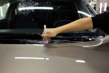 A person is cleaning a car windshield with a brush and water