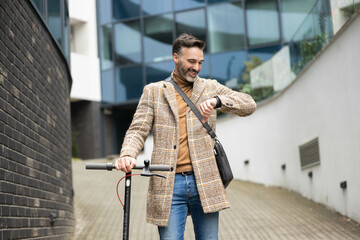 a stylish man in a checkered coat standing beside a scooter, checking his smartwatch with a modern...