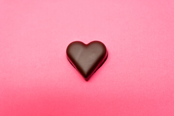 Fototapeta premium Chocolate heart set against a pink background. Love, romance, Valentine's Day themes. Abstract background. 