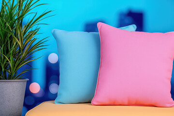 Soft pastel cushions in blue and pink on vibrant rooftop with city lights