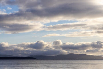 Scenic Sunrise Over Mountains and Ocean With Cloudy Sky Display