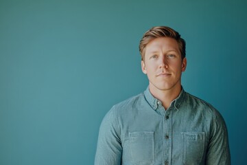Obraz premium Confident Young Man Posing Against a Blue Background in Casual Attire