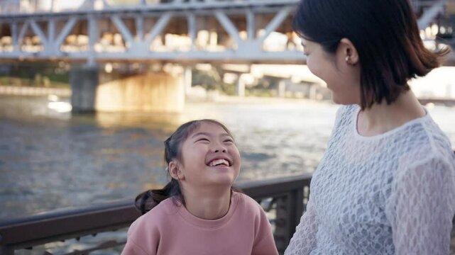 Mother and daughter sharing a laugh by sumida river in tokyo