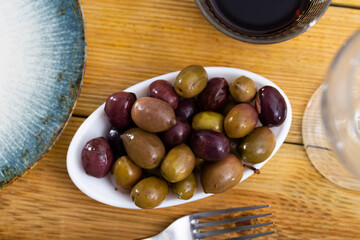 Large black and green olives on a white plate. Natural Italian olives from the farm for salad