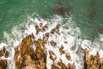 Bird eye view seashore with waves crashing on rock cliff, Beautiful waves sea surface in sunny day summer background, Amazing seascape top view seacoast landscape view