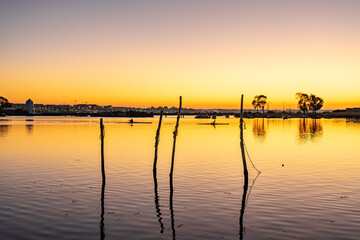 Obraz premium Tranquil water from a river at sunset with small recreational or fishing boats
