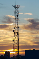 Antena de comunicación en atardecer en ámbito urbano. Antena de emisión de señales de radio,...