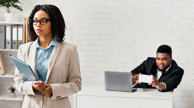 Sexual molestation at workplace. Perverted black guy taking photo of his female coworker without her consent at company office, blank space. Gender discrimination and career concept