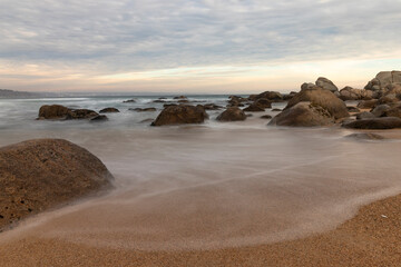 atardecer en la playa  junto a las rocas y las olas