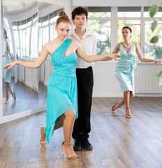 Dance teacher teaches a girl and boy couples ballroom dancing