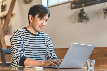 カフェ・喫茶店・コワーキングスペースで仕事をする中年男性ビジネスマン（副業・フリーランス）
