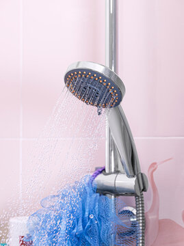 Removable shower head placed on its support and sprying water intp the shower.