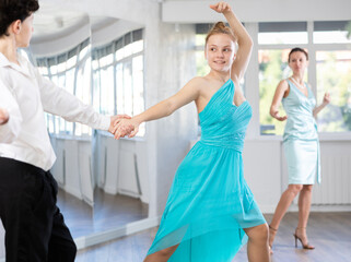Passionate young ballroom enthusiasts, teenage girl and boy practicing graceful waltz routine in...