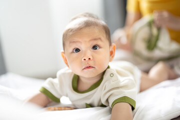 Fototapeta premium Asian newborn baby boy lying on the floor playing with colorful kid toys. Happy baby boy in kindergarten or daycare. Child playing with colorful educational toys in preschool. Asian boy. 