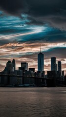 A city skyline at dusk with a dramatic sky filled with clouds and streaks of light.