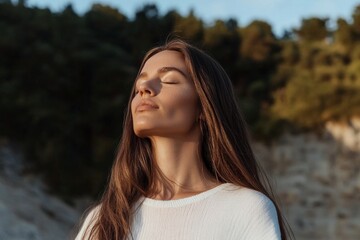 Fototapeta premium A woman with long brown hair is sitting in the sun