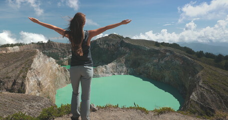 Female tourist is embracing the beauty of nature while standing on the edge of a crater lake with turquoise water. She is enjoying the view of the volcano crater in the philippines