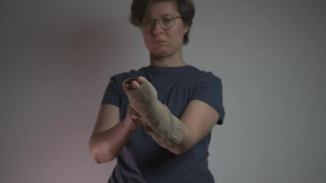 Woman puts on compression sleeve for vein health on her arm, aiding in thrombosis and embolism prevention. This medical garment supports circulation and helps manage varicose veins and venous issues. 