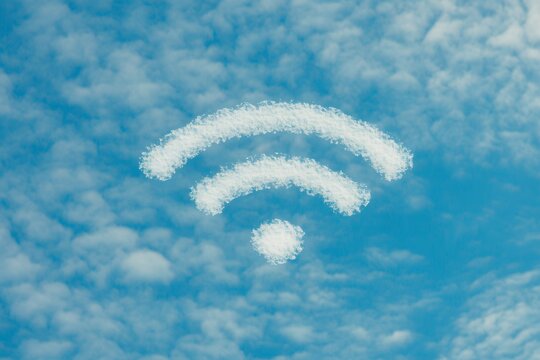 A creative cloud formation resembles a wifi symbol in a bright blue sky with soft clouds. Generative AI