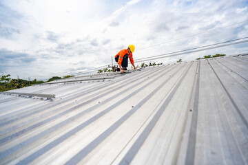 Technician in safety uniform and helmet kneeling on a rooftop, using a drill for precise installation work. A scene highlighting safety, professionalism, and technical expertise in construction.