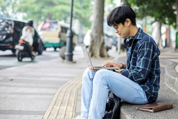 Young Man Working on Laptop Outdoors in Urban Setting	