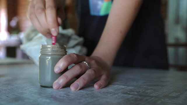 Close-up of hands mixing clay slip with a stick in slow motion, showcasing sustainable artistry and natural materials. Perfect for themes of eco-friendly crafts, pottery, and mindful creativity.