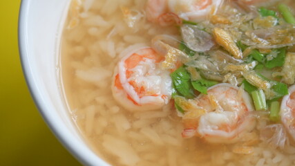 rice soup with shrimp in white bowl on yellow background