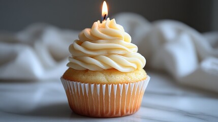 Vanilla cupcake with creamy frosting and lit candle